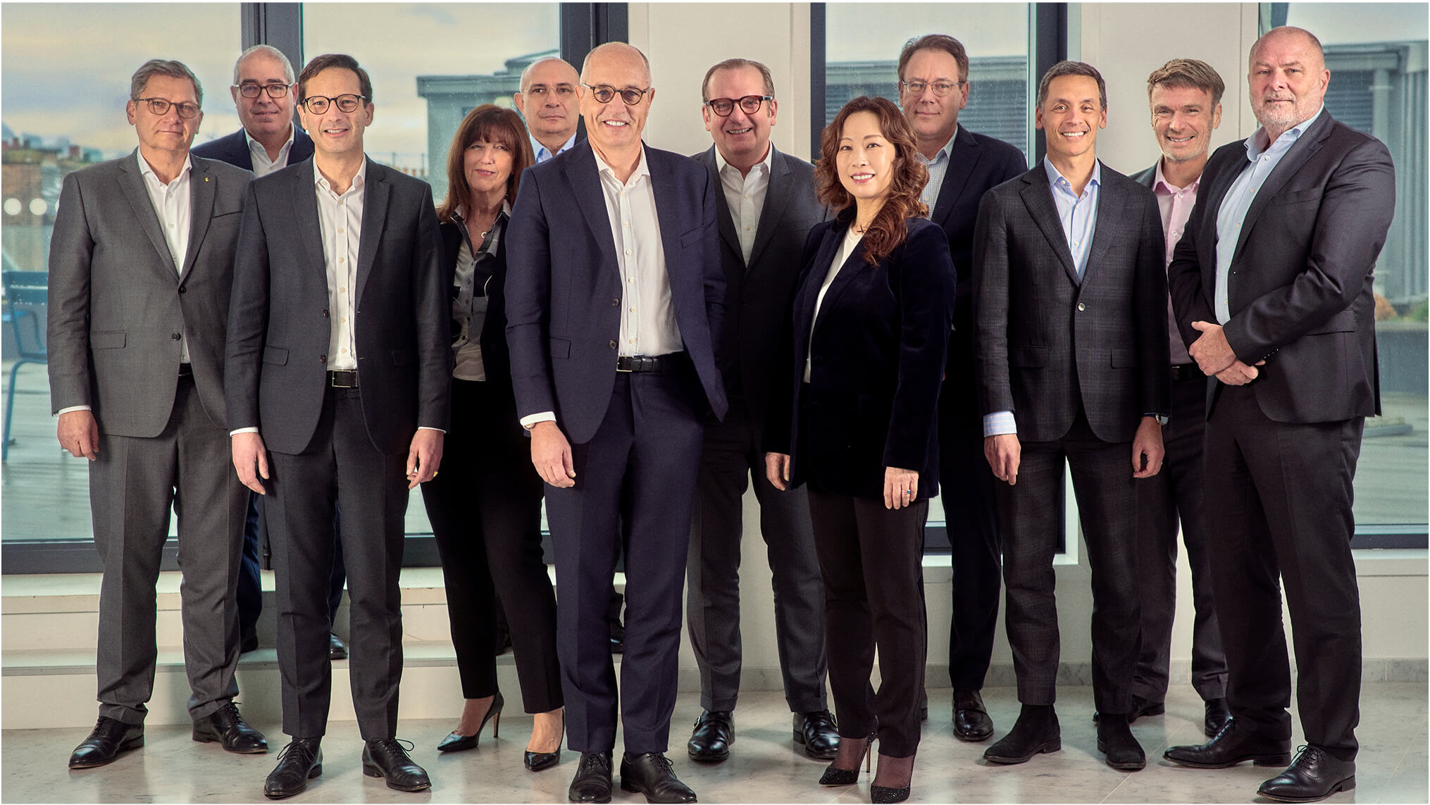 Plusieurs personnes alignées pour une photo de groupe à l'intérieur d'un bureau