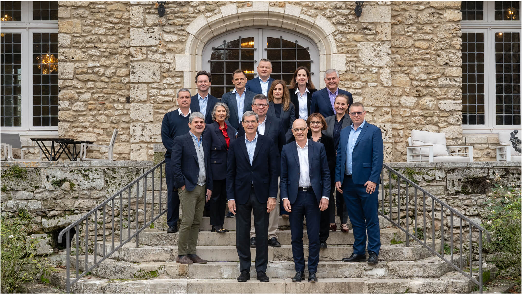 Plusieurs personnes alignées pour une photo de groupe devant un immeuble ancien.