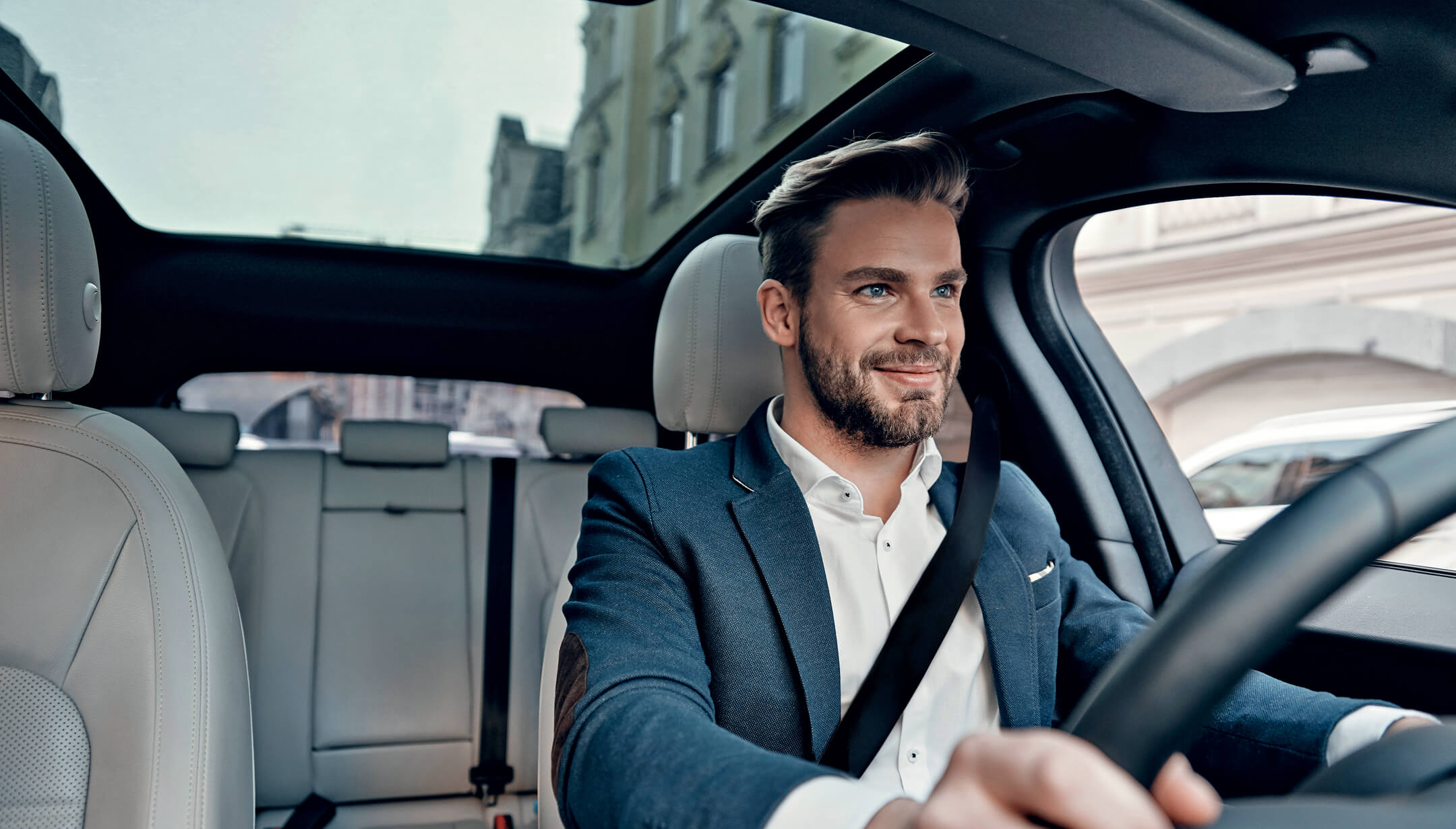 A smiling driver seen from the front inside a car