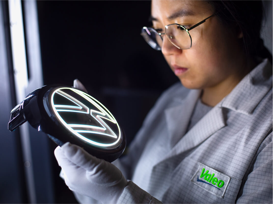 A woman inspecting the illuminated Volkswagen logo