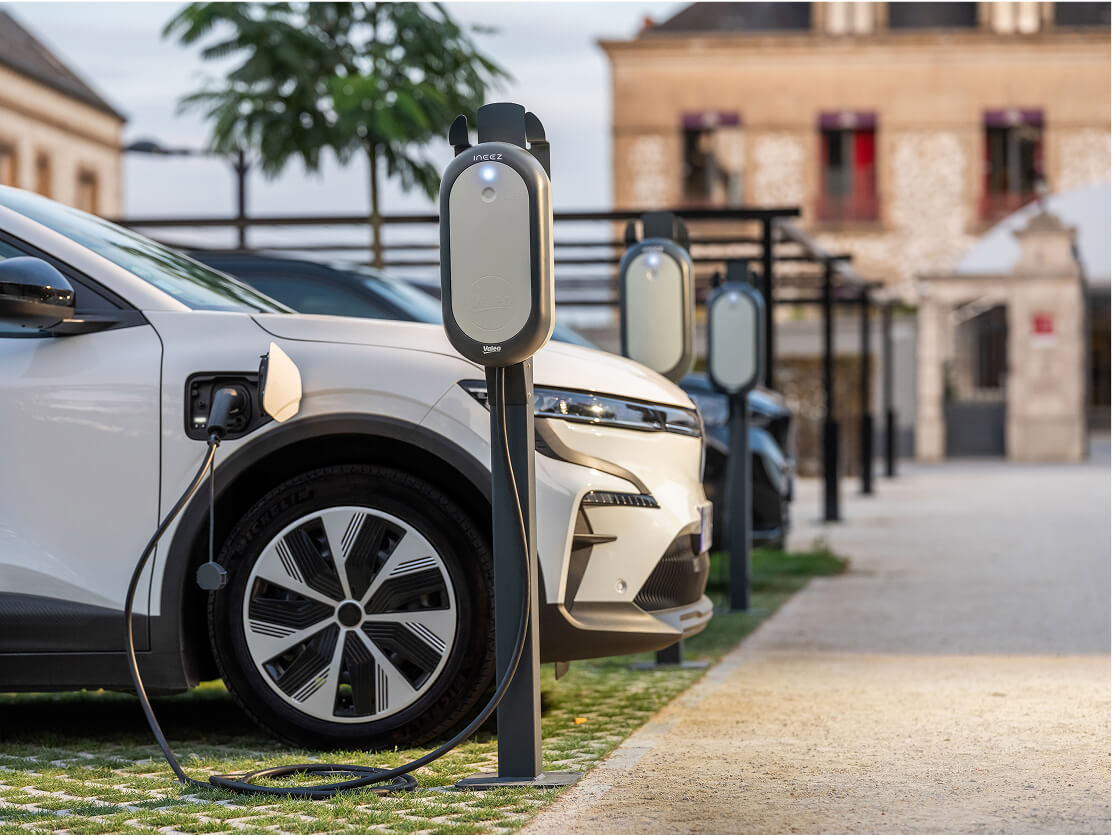 A parking lot of electric vehicles lined up in front of charging stations