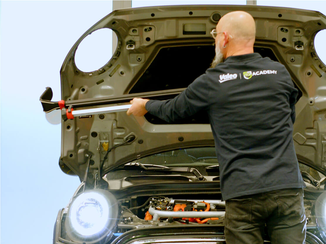 A person standing in front of an open car hood