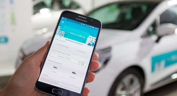 A woman using the Valeo Mov'In Blue App to reserve a vehicle using her smartphone