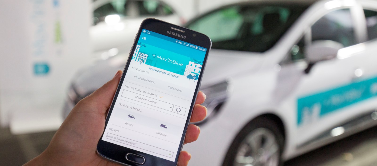 A woman using the Valeo Mov'In Blue App to reserve a vehicle using her smartphone